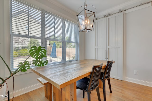 dining area with crown molding, light wood-style flooring, baseboards, and a chandelier