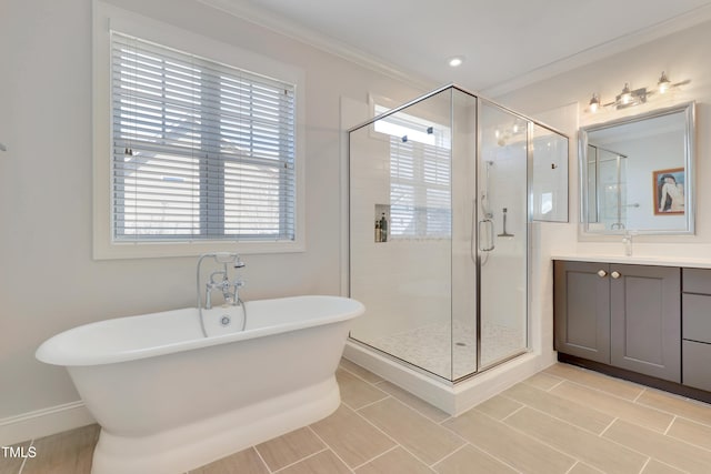 full bath featuring crown molding, vanity, a freestanding tub, baseboards, and a shower stall