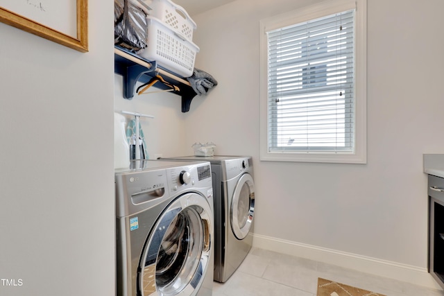 laundry room with laundry area, baseboards, light tile patterned floors, and washing machine and dryer