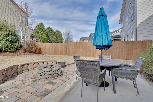 view of patio featuring a fenced backyard, outdoor dining space, and an outdoor fire pit