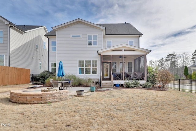 rear view of house with ceiling fan, roof with shingles, a sunroom, a fenced backyard, and an outdoor fire pit