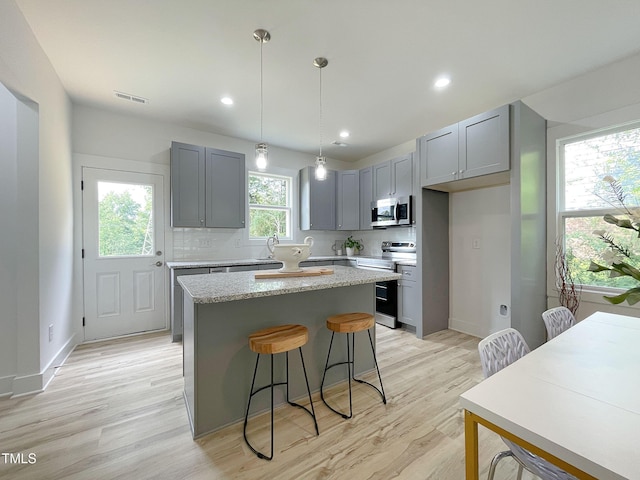 112 Remington Woods Dr, Wake Forest, NC 27587 - kitchen with stainless steel appliances, gray cabinets, a kitchen island, light wood-style flooring, and recessed lighting