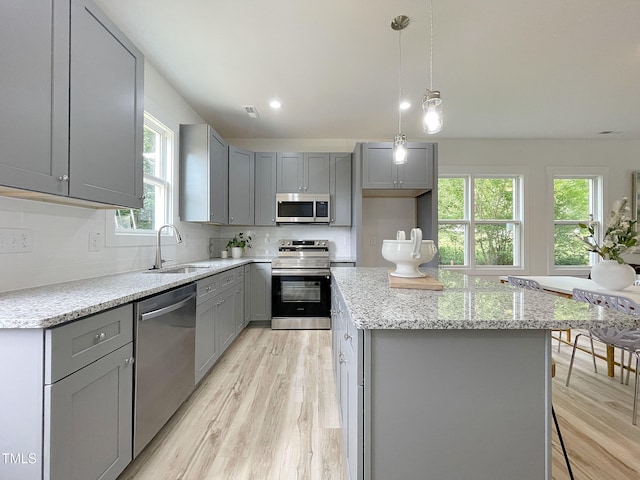 112 Remington Woods Dr, Wake Forest, NC 27587 - kitchen featuring stainless steel appliances, gray cabinets, a sink, light wood-style floors, and light stone counters