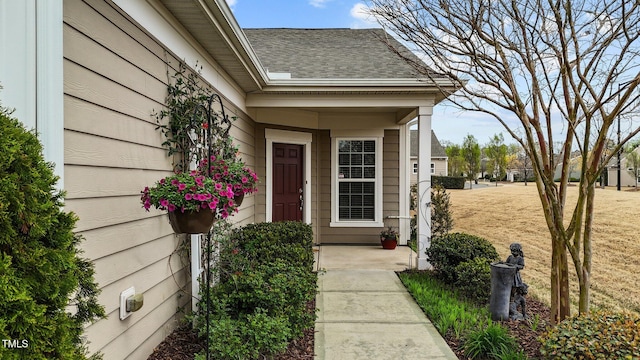 property entrance with a lawn and roof with shingles