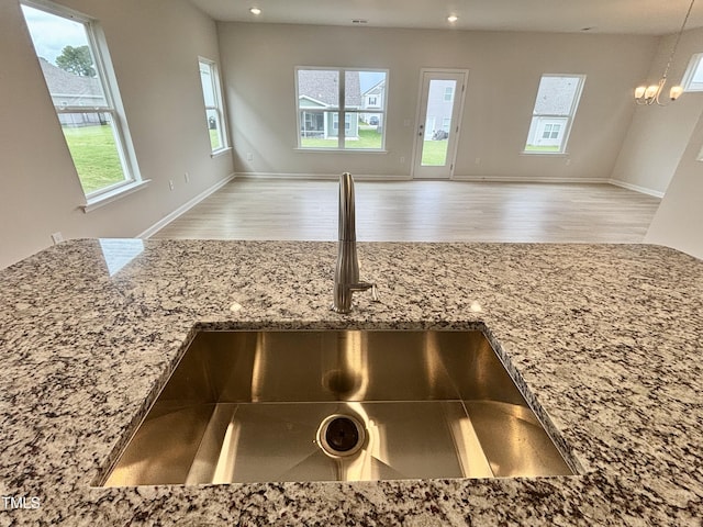 76 Commons Cir, Clayton, NC 27520 - kitchen view of a sink, light stone counters, wood finished floors, a chandelier, and recessed lighting