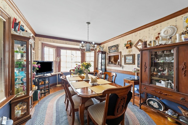 dining room featuring wallpapered walls, crown molding, wood finished floors, and a notable chandelier