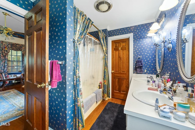 full bathroom featuring crown molding, wallpapered walls, a sink, visible vents, and wood finished floors
