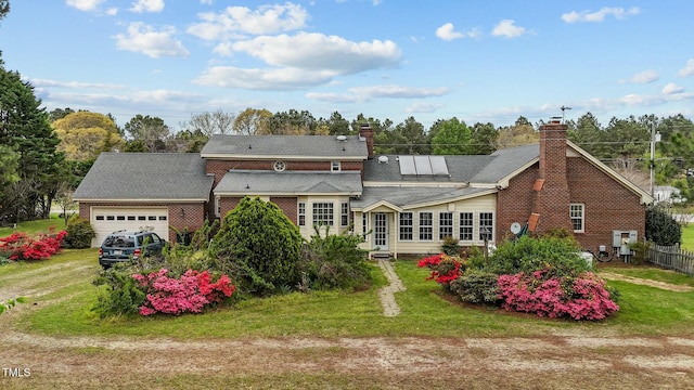 back of property featuring a lawn, a chimney, a garage, and driveway