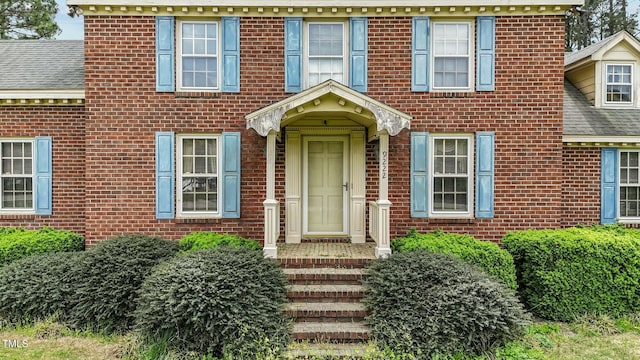 view of front of property featuring brick siding and a shingled roof