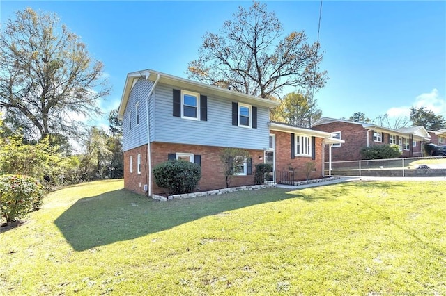 split level home featuring brick siding, fence, and a front yard