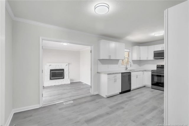 kitchen with white cabinets, a sink, stainless steel appliances, and light wood finished floors