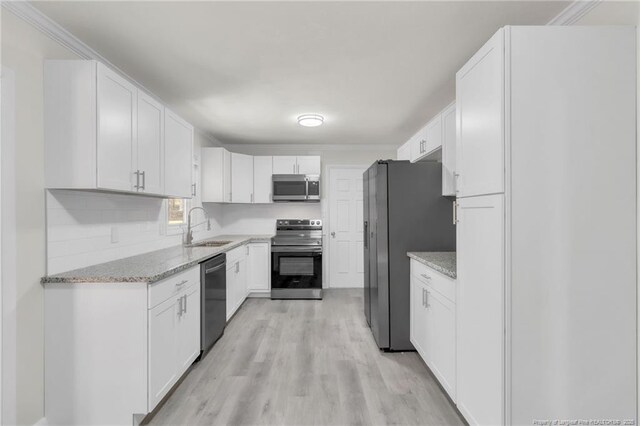 kitchen featuring white cabinetry, a sink, stainless steel appliances, and light stone countertops