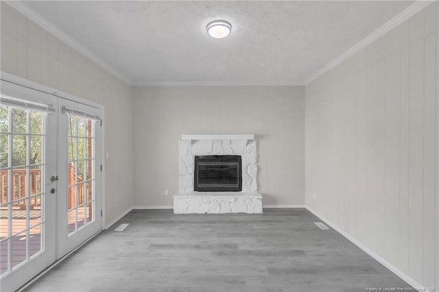 unfurnished living room featuring french doors, wood finished floors, ornamental molding, and a premium fireplace