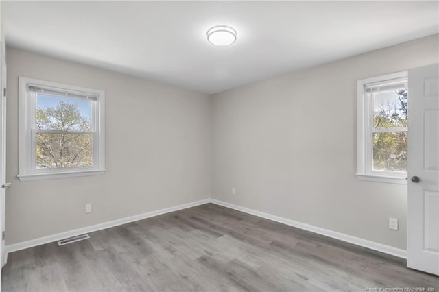 spare room with wood finished floors, baseboards, and visible vents