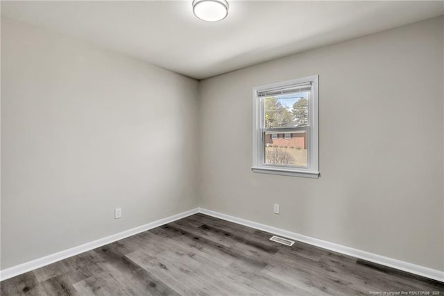 empty room featuring baseboards, visible vents, and wood finished floors