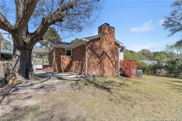view of home's exterior with stairs, brick siding, a yard, and a chimney