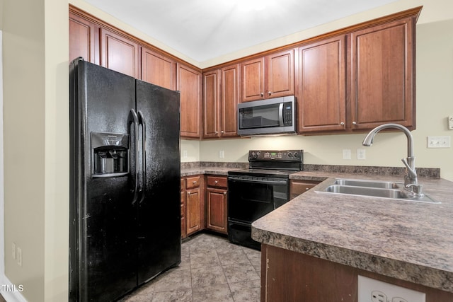kitchen with dark countertops, brown cabinetry, black appliances, and a sink