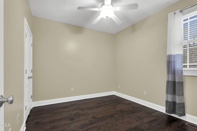 spare room with baseboards, visible vents, a ceiling fan, and dark wood-type flooring