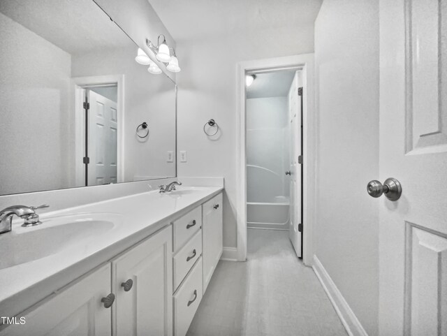 full bathroom with double vanity, a sink, baseboards, and a bath