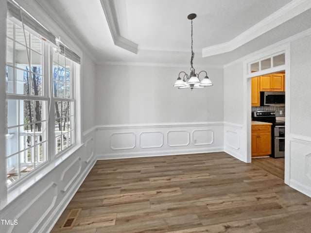 unfurnished dining area featuring visible vents, crown molding, wood finished floors, a raised ceiling, and a notable chandelier