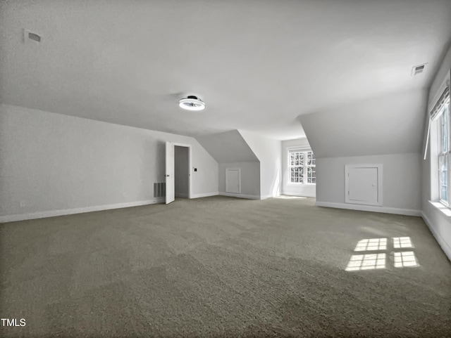 additional living space with carpet floors, baseboards, lofted ceiling, and visible vents