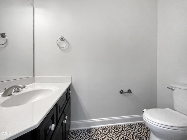 half bath featuring baseboards, toilet, tile patterned floors, and vanity