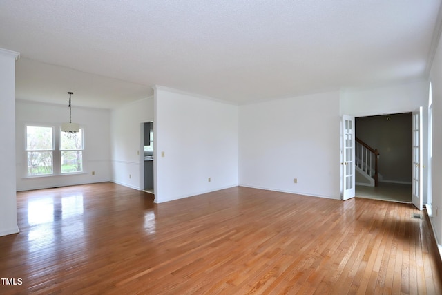3313 Sparrowhawk Dr, High Point, NC 27265 - unfurnished living room with light wood-type flooring, an inviting chandelier, baseboards, and stairway