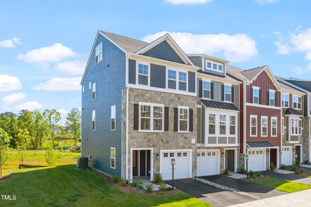 townhome / multi-family property featuring central air condition unit, an attached garage, stone siding, driveway, and a front yard