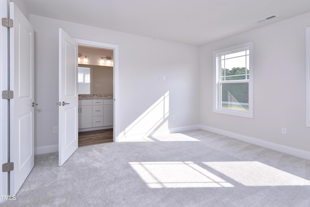 unfurnished bedroom with baseboards, multiple windows, light colored carpet, and visible vents