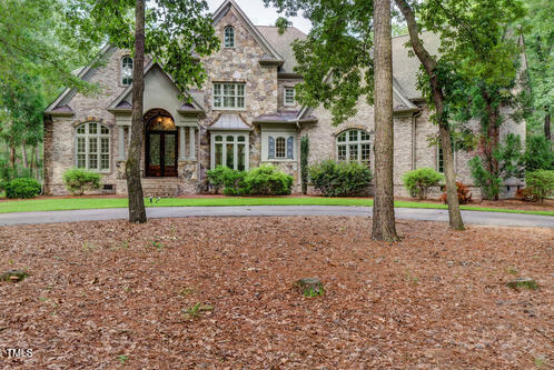 view of front facade featuring french doors, stone siding, and curved driveway