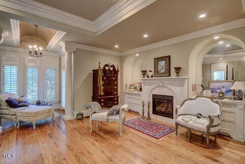 sitting room with crown molding, recessed lighting, a chandelier, a glass covered fireplace, and wood finished floors