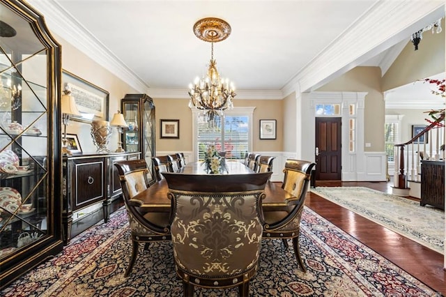 dining space featuring a healthy amount of sunlight, wood finished floors, a chandelier, and a wainscoted wall