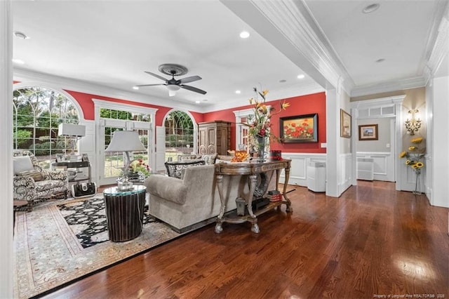 living room with crown molding, a wainscoted wall, ceiling fan, a decorative wall, and wood finished floors