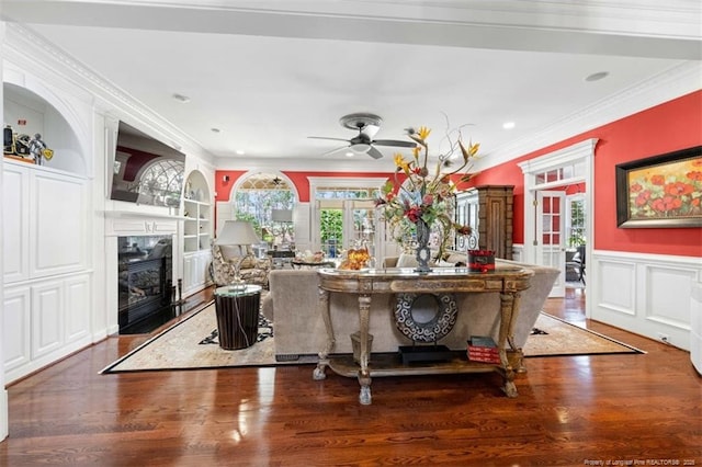 living area featuring a premium fireplace, wood finished floors, ornamental molding, and built in shelves