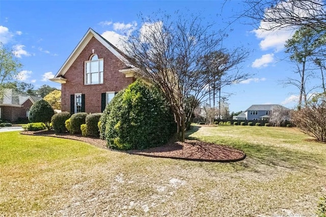 view of property exterior with brick siding and a yard