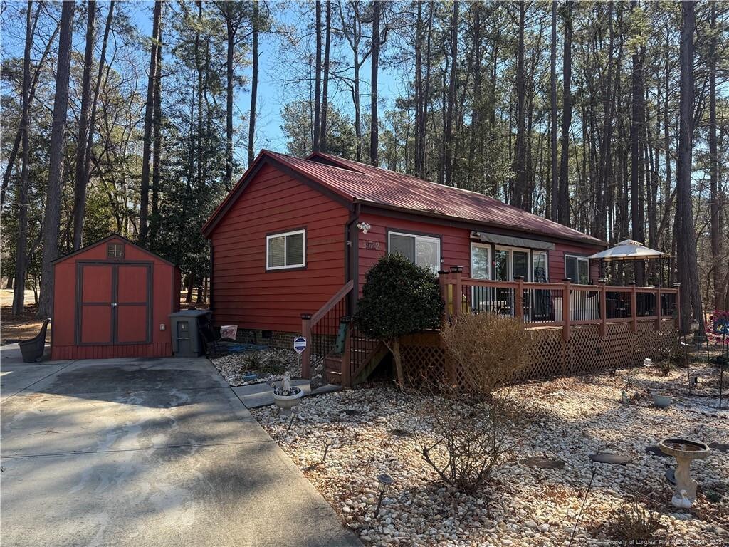 view of front of home with metal roof, a deck, an outdoor structure, and a storage shed