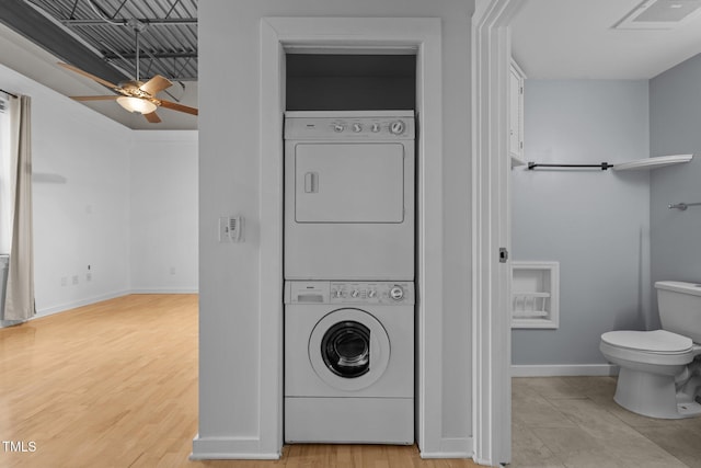 clothes washing area with baseboards, stacked washer and dryer, visible vents, laundry area, and ceiling fan