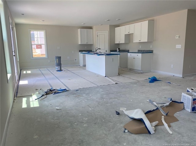4894 Blue Springs Rd, Red Springs, NC 28377 - kitchen with a kitchen island with sink, white cabinets, dark countertops, and baseboards