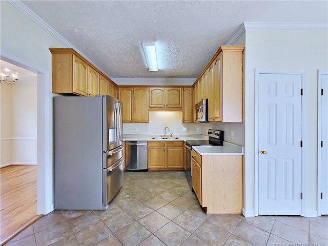 kitchen with light countertops, ornamental molding, a textured ceiling, a sink, and appliances with stainless steel finishes