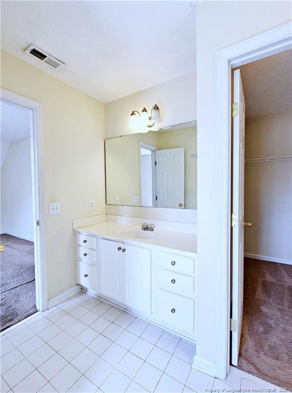 bathroom with tile patterned flooring, vanity, baseboards, and visible vents