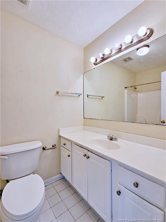 bathroom featuring toilet, vanity, a textured ceiling, tile patterned flooring, and visible vents