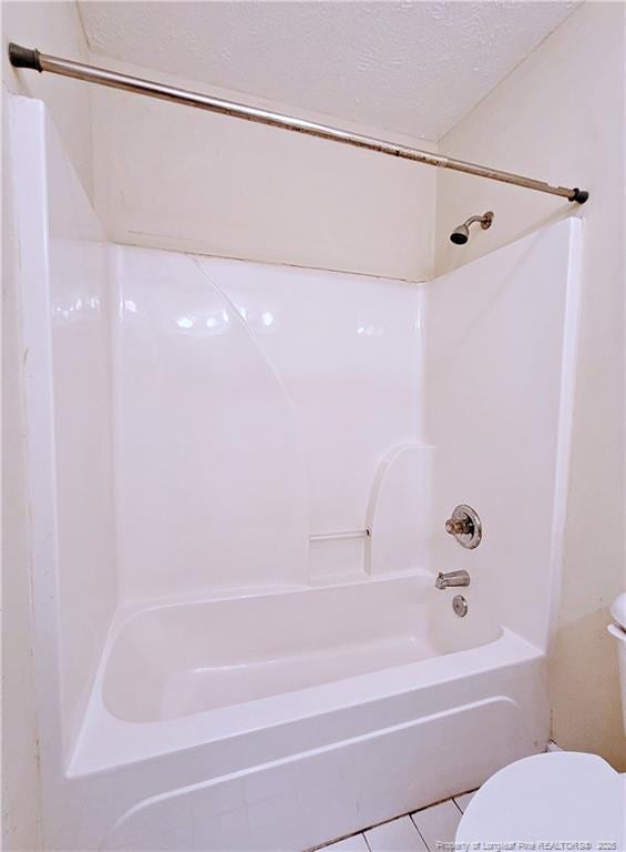 full bath featuring  shower combination, a textured ceiling, toilet, and tile patterned floors