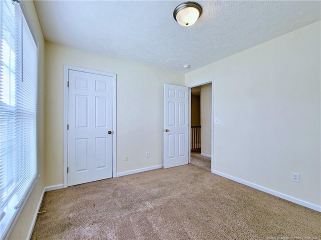 unfurnished bedroom with carpet floors, baseboards, and a textured ceiling