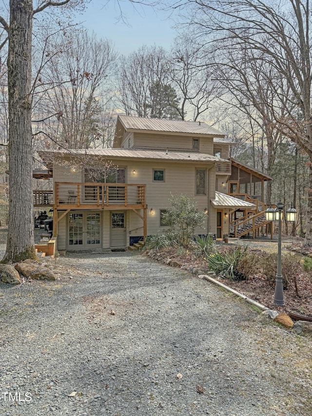 rear view of house with metal roof, gravel driveway, a deck, and french doors