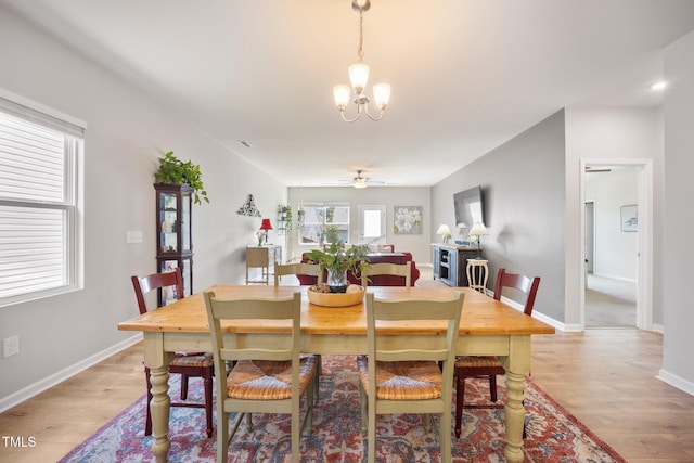 dining space with a chandelier, light wood-style flooring, a ceiling fan, and baseboards