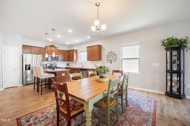 dining space featuring a chandelier, light wood finished floors, recessed lighting, and baseboards