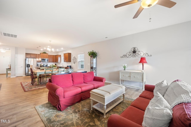 living area with light wood-type flooring, ceiling fan, a chandelier, and baseboards
