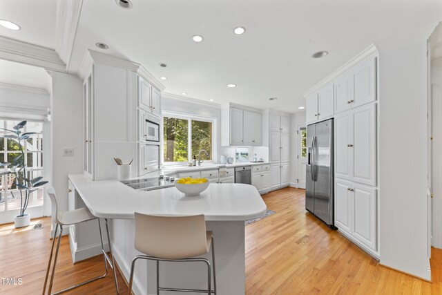 3911 Hope Valley Rd, Durham, NC 27707 - kitchen featuring stainless steel appliances, a peninsula, light wood-style flooring, white cabinets, and recessed lighting