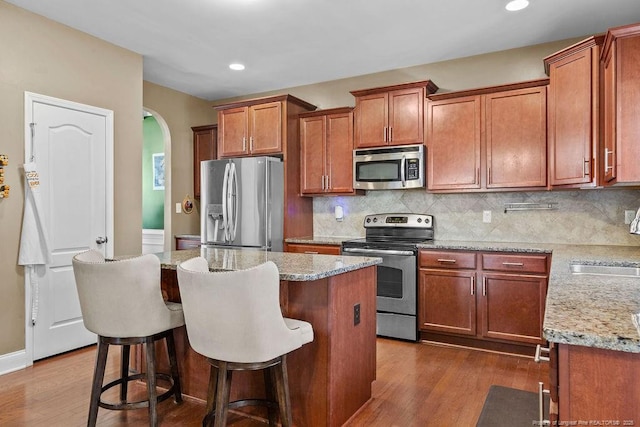 178 Tun Tavern Dr, Cameron, NC 28326 - kitchen featuring appliances with stainless steel finishes, dark wood-style floors, arched walkways, a kitchen island, and decorative backsplash