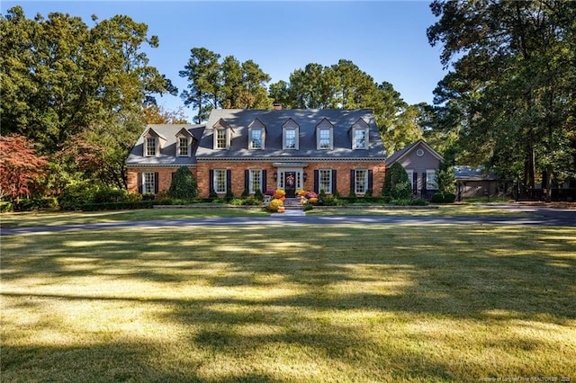 cape cod home featuring brick siding and a front lawn